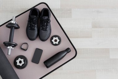 Dambıllar, ayakkabılar, su şişesi, saat ve telefon, fotokopi alanı olan spor minderi.