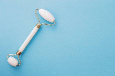 Fotokopi alanı olan mavi arkaplan üzerinde yüz bakımı için düz bir masaj silindiri