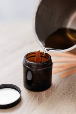 Sarı sıvı tavadan siyah cam şişeye dökülüyor.