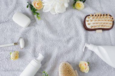 Banyo aksesuarları ve gri havludaki çiçekli kompozisyonun üst görünümü