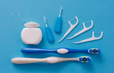 Mavi arka planda beyaz diş ipi, kürdan ve fırça.