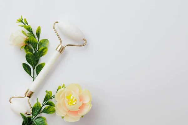 Weiße Gesichtsmassagerolle Und Blumen Auf Weißem Hintergrund Mit Kopierraum — Stockfoto