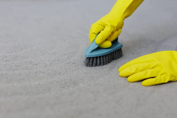 用刷子把双手紧握在黄色手套中 用刷子刷洗地毯 复制空间 — 图库照片