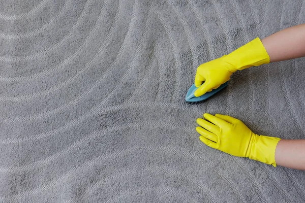 纯度和清洁概念 用刷子刷洗黄色橡胶手套地毯的双手顶部视图 在灰色地毯上复制空间 — 图库照片