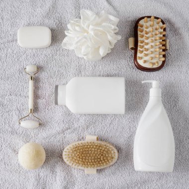 Gri havlunun üzerinde banyo aksesuarları olan düz kompozisyon.