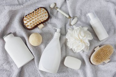 Gri havluda banyo aksesuarları olan kompozisyonun üst görüntüsü