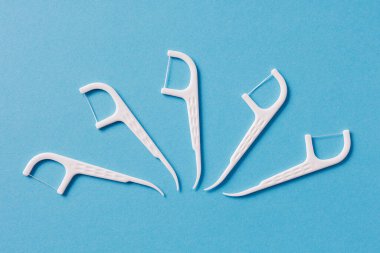 Mavi arka planda diş ipi olan bir sürü beyaz diş kürdanı.