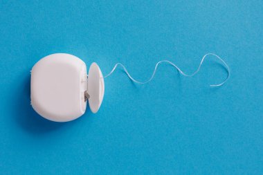 Mavi arka planda diş temizliği için beyaz diş ipi