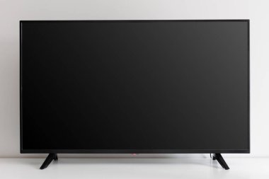 Beyaz duvara karşı beyaz klozette boş siyah televizyon ekranı