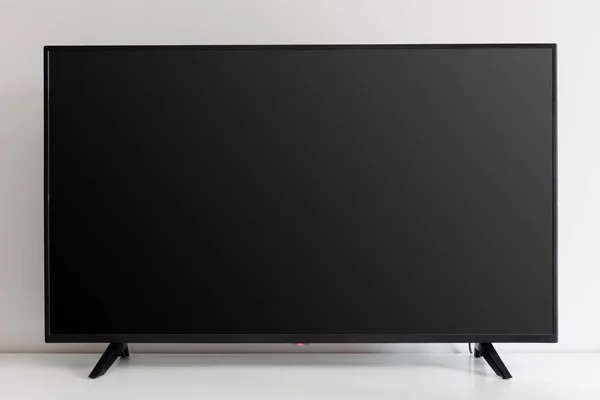 Beyaz duvara karşı beyaz klozette boş siyah televizyon ekranı