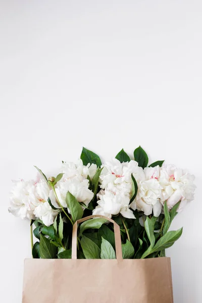 コピースペース付きの茶色の紙袋に美しい白い牡丹と葉 — ストック写真