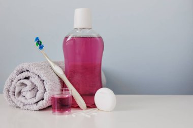 Masada pembe gargara, diş fırçası, havlu ve diş ipi var.