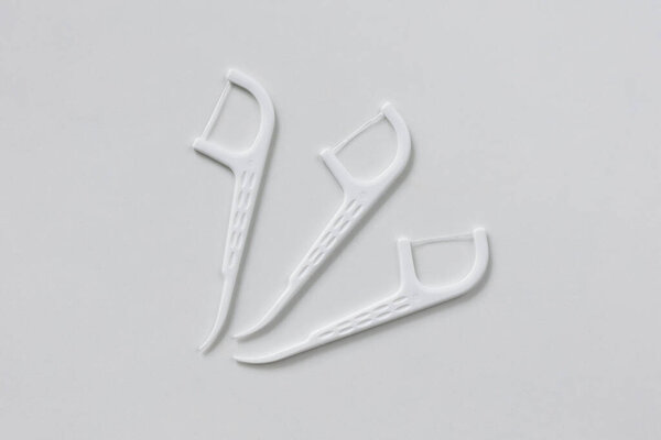 White dental toothpicks with dental floss on white background