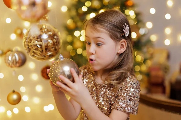 Funny Little Girl Holding Golden Christmas Ball Decorated Room Stock Photo