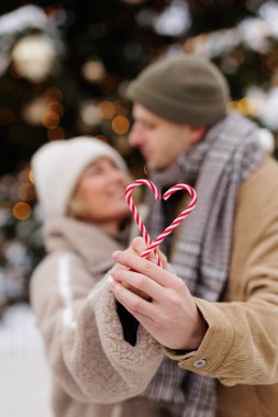Noel tatili için baston şeker taşıyan iki elin yakın çekimi.