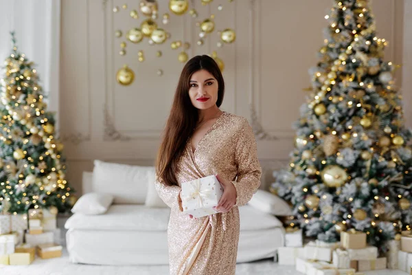 Güzel bir kadın Noel süslemeli bir odada elinde hediyeyle.