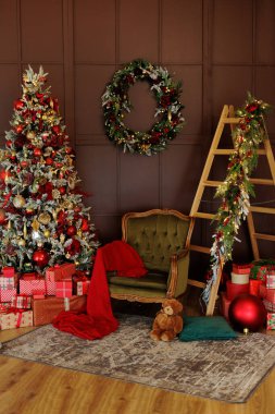 Koltuk, merdiven ve oturma odasında kırmızı hediyeler olan Noel ağacı.