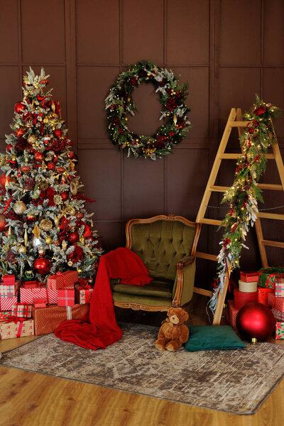 Armchair, ladder and christmas tree with red gifts in living room