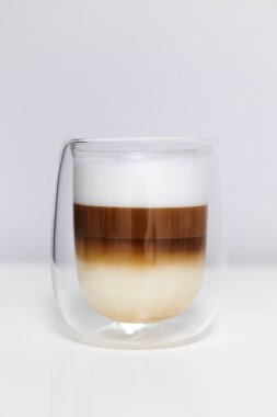 Beyaz masadaki sütlü duble cam sütlü kahve.