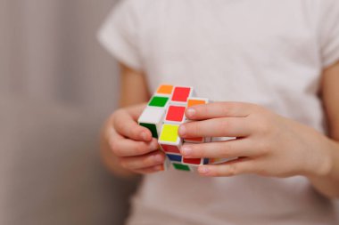 Küçük kızın ellerinde renkli Rubik küpünü kapat.