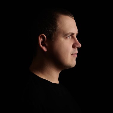 Karanlık arka planda mutlu genç bir adamın yan görünümü