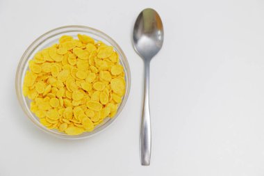 Cam kasede servis edilen mısır gevrekleri. Beyaz arka planda kaşık ve kopyalama alanı var.