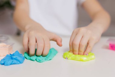 Masada yeşil ve sarı sümüklü ellerle oynarken ellerini kapat.