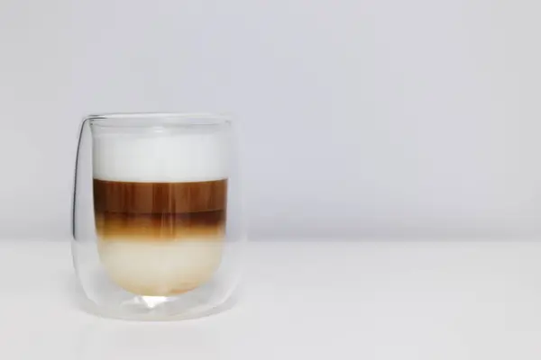 double glass cup of fresh latte coffee with milk on white table and copy space