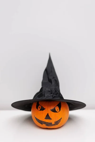 Halloween orange pumpkin with witches hat on table