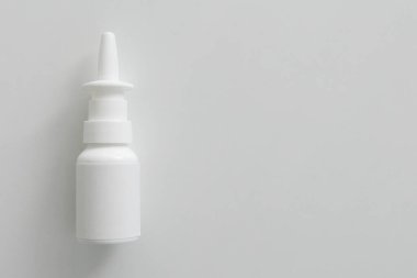 Beyaz bir masada üzerinde burun spreyi etiketi olmayan beyaz şişe.