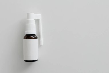 Boğazına sprey sıkılmış beyaz bir şişe ve kopyalanmış bir masa.