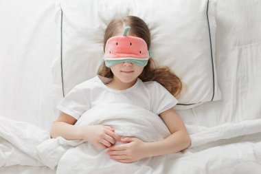 Karpuz maskesiyle battaniyenin altında uyuyan tatlı küçük kız manzarası.