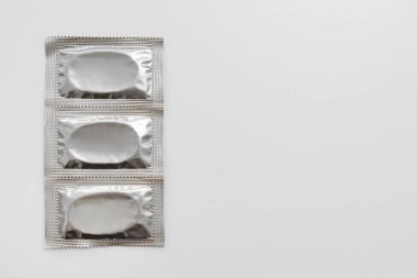 Telif alanı beyaz olan üç gümüş paket prezervatifi kapat