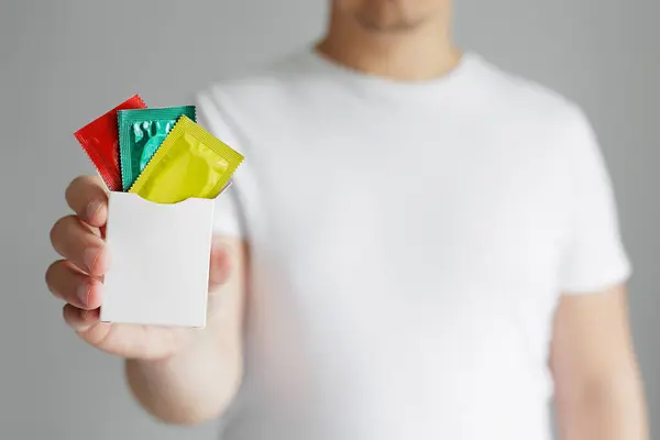 Man Toont Pakket Van Kleurrijke Condooms Met Copyspace Stockafbeelding