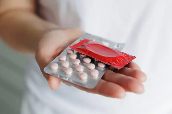 Großaufnahme Der Hand Einer Frau Die Eine Rote Packung Kondom lizenzfreie Stockfotos