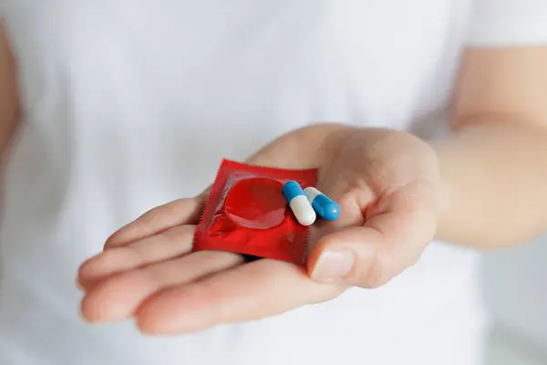 Frauenhände Mit Rotem Kondom Und Pillen Stockbild