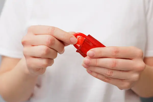 Detailní Záběr Ženy Bílém Tričku Otvírá Červený Kondom Stock Fotografie
