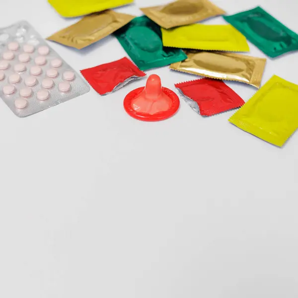 许多色彩艳丽的避孕套和带有彩色背景的药丸 免版税图库图片