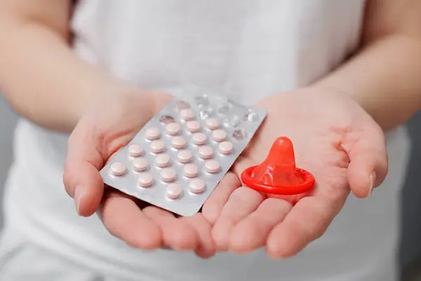 Närbild Kvinnor Händer Med Röd Kondom Och Piller Stockbild