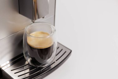 Kahve makinesindeki çift katlı espresso bardağını kapat ve beyaz masanın üzerine boşluğu kopyala