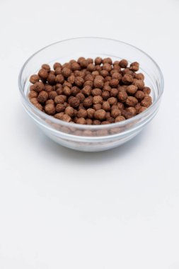 Telif alanı olan cam kasede gevrek çikolatalı kahvaltı toplarının üst görüntüsü.