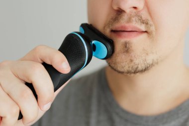 Genç adam siyah bir makasla sakalını kesiyor.