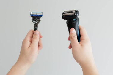 Adamın elleri beyazın üzerinde ustura ve elektrikli makina tutuyor.