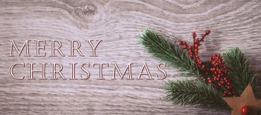 Christmas greeting card - White burning candle with natural decoration on rustic light wood - Merry Christmas and happy new year