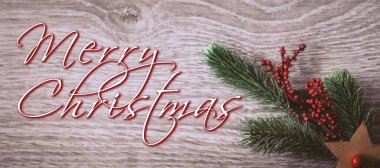 Christmas greeting card - White burning candle with natural decoration on rustic light wood - Merry Christmas and happy new year