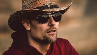 Portrait of a man wearing a hat and glasses. Cowboy in summer.