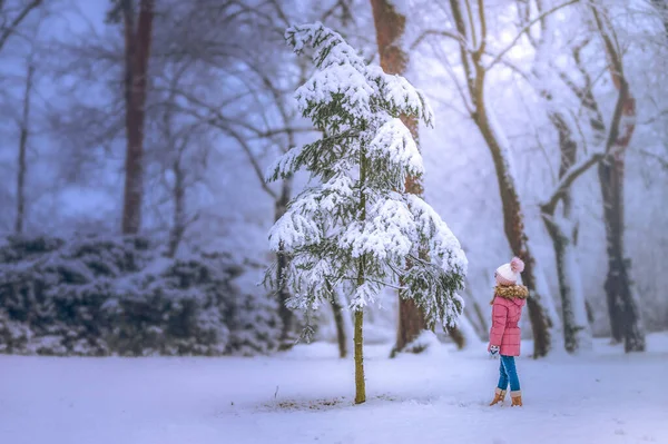 A little girl walks away through a snowy landscape. Beautiful winter atmosphere. Snow-covered trees.