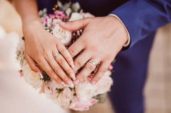Yeni evlilerin ellerinin ayrıntıları. Gelinin ve damadın elleri. Yüzüklerin düğün fotoğrafları.