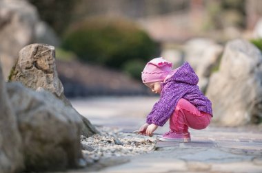 Küçük bir çocuk çakıl taşı toplar. Küçük bir kız oynuyor.. 