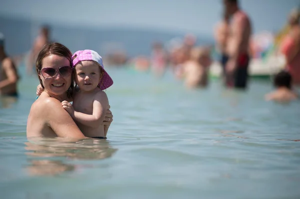 stock image Mom and daughter playing in the water. Childhood. Family in the sea.